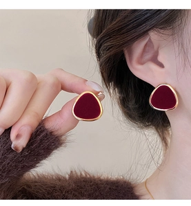 Close-up of vintage deep red velvet triangle stud earrings with elegant gold metal edges