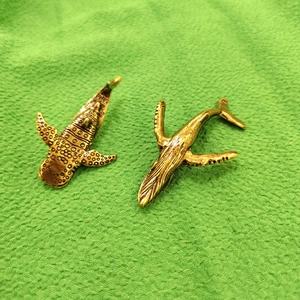Vintage gold metal whale shark and humpback whale miniature sculptures on a green fabric base