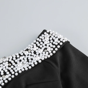 Close-up of elegant white pearls and sparkling diamonds on black knit evening dress