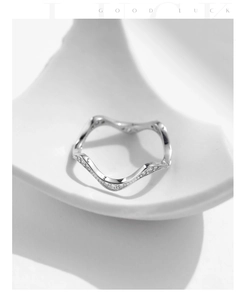 Macro shot of silver wave-shaped ring with micro-pave cubic zirconia on white tray