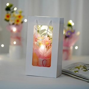 Handgemachter rosa gestrickter Puffblumenstrauß in weißer Geschenktüte mit LED-Lichtern
