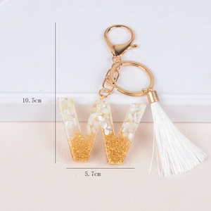 Detailed view of resin letter W keychain with gold flakes and white shell fragments