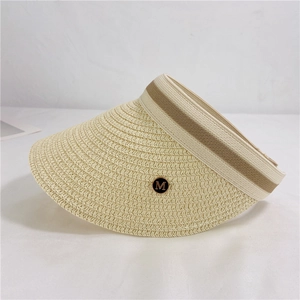 Detail of beige straw sun visor with brown ribbon and gold M metal letter emblem