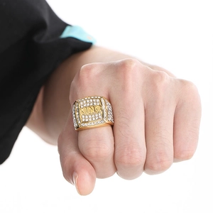 Macro detail of gold hip hop ring featuring KING engraving and paved rhinestones