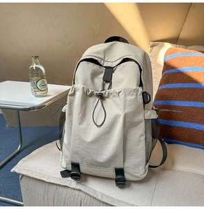 Details eines cremefarbenen Rucksacks mit Kordelzug-Vordertasche und seitlichem Netzfach