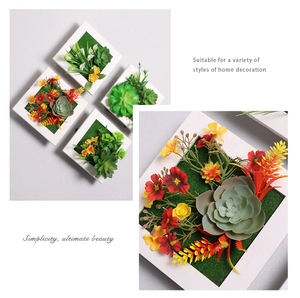 Close-up of artificial succulents and flowers in a white square frame wall decoration
