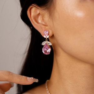Gros plan de boucles d'oreilles de luxe en zircon rose avec monture dorée fleurie