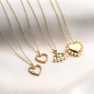 Detail of gold-plated necklaces with pearl heart pendants and evil eye on white silk