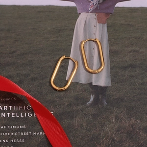 Detail of 18K gold plated stainless steel oval hoop earrings on fashion magazine background