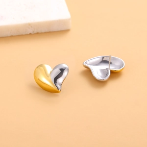 Detailed macro view of minimalist heart stud earrings in two-tone gold and silver finish