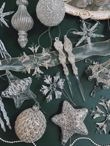 Detailed view of silver glitter snowflakes and star ornaments on dark green background