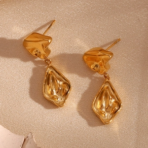 Macro detail of gold-plated geometric earrings with irregular lava-style texture