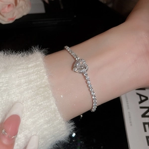 Macro shot of a silver heart tennis bracelet featuring sparkling cubic zirconia on wrist