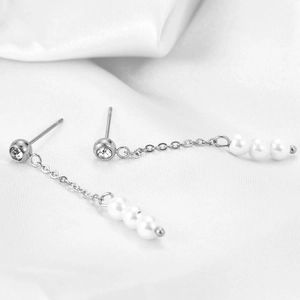 Macro shot of 18K gold earrings featuring long tassels with white pearls and sparkling zircons