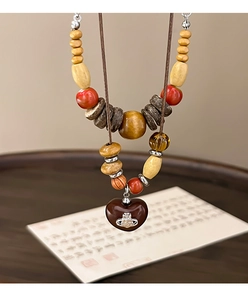 Detailed macro view of Bohemian beaded necklace featuring a brown heart and Saturn logo