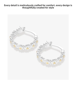 Close-up of geometric S925 sterling silver daisy hoop earrings with gold accents
