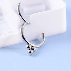 Macro shot of silver stainless steel hinged segment ring with three metal beads on blue background