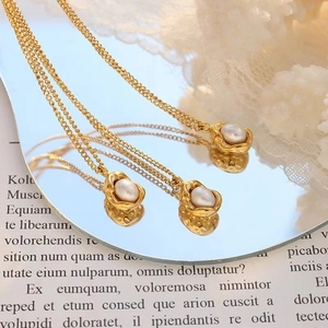 Irregular textured gold pendant necklace with a single white pearl on retro newspaper