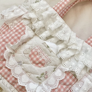 Detail of pink plaid quilted handbag with white lace layers and rose embroidery
