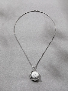 Détail du pendentif en marbre blanc serti de strass sur chaîne argentée