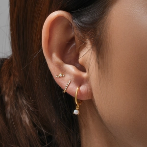 Close-up of gold Evil Eye earring set with opal and cubic zirconia on a female model