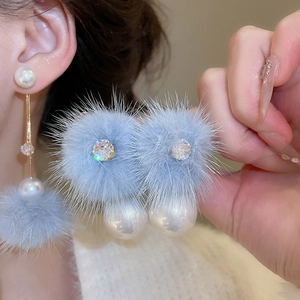 Detail of blue faux fur pom pom earrings with white pearl and sparkling crystals