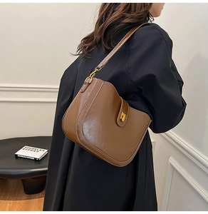 Detail of vintage brown saddle shoulder bag with retro gold clasp closure for women