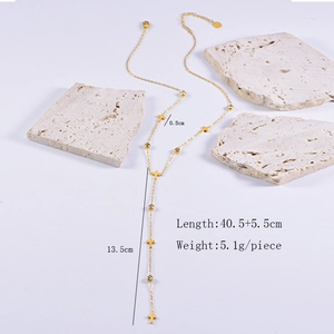 Detail view of gold Y-necklace with cross and gem charms showing 40.5+5.5cm dimensions