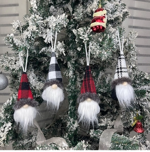 Close-up of four Christmas gnome hanging ornaments with festive patterns on a snowy tree