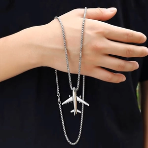 Close-up of silver airplane pendant necklace held by hand showing detailed box chain