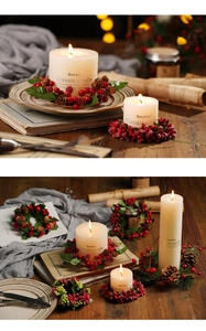 Detailed view of white pillar candles with red berry and pinecone Christmas wreaths