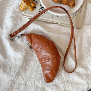 Chic brown PU leather croissant-shaped mini bag with metallic buckles on white fabric