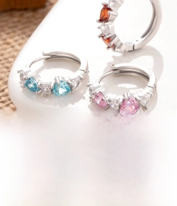 Detailed macro shot of 10mm silver heart zircon earrings in blue, pink and orange colors