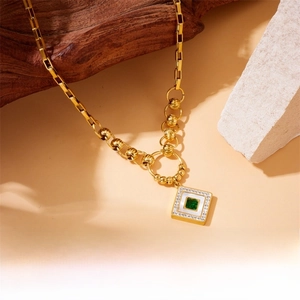 Macro shot of gold necklace with emerald square stone and multilayered chain details
