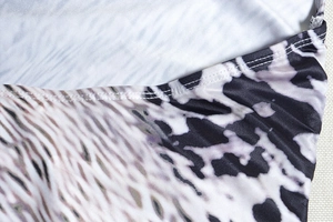 Macro shot of snakeskin print dress fabric with precise white flat-lock stitching detail