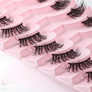 Close-up of voluminous black false eyelashes arranged on a pink wavy display tray
