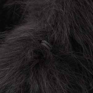 Detailed macro view of dark faux fur texture with delicate braided rope buckle closure
