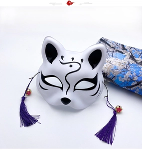 Detail of hand-painted Japanese fox mask with purple tassel bell and blue sakura fabric