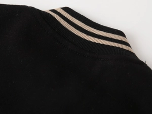 Close-up of black baseball jacket collar with striped knit ribbing and neat stitching