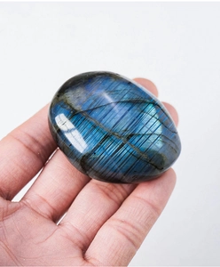 Close-up of smooth oval labradorite stone with vibrant blue iridescence held in hand