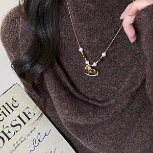 Close-up of vintage horse pendant with pearls and brown beads on a sweater