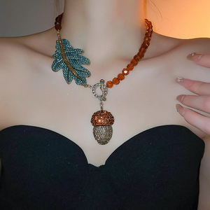 Vue détaillée du collier pomme de pin avec feuilles en strass bleus et perles ambrées