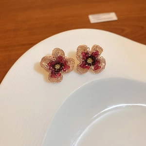 Detail of flower earrings featuring gold-lined petals and deep red beaded centers