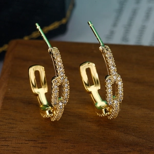 Exquisite goldene geometrische C-Ohrringe mit glitzerndem Zirkon auf Holzsockel