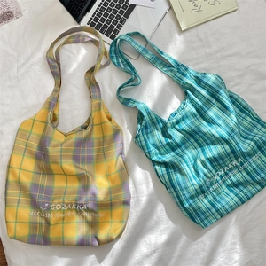 Detailed overhead view of large capacity plaid canvas tote bags in warm and cool color tones