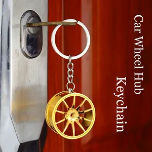 Golden alloy car wheel rim keychain with polished finish attached to door key