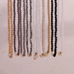 Detail of colorful faceted bead necklaces with irregular pearls on a white wall