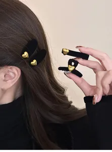 Dettaglio del fermaglio per capelli in velluto nero con cuore dorato e incisione