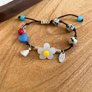 Bracelet fait main en perles avec fleurs, cœurs et cordon marron sur bois naturel