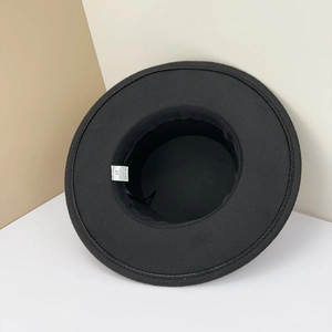 Detail of white care label inside a black wool felt hat showing 58cm size and fabric mix